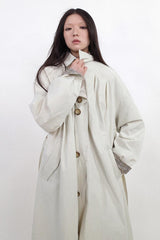 Waist-cinched, straight-cut, with a plaid patchwork design and raglan sleeves, this trench coat features a bold silhouette.