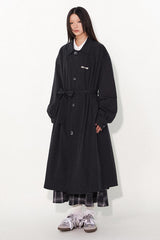 Waist-cinched, straight-cut, with a plaid patchwork design and raglan sleeves, this trench coat features a bold silhouette.