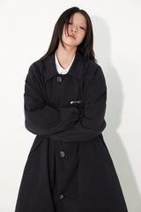 Waist-cinched, straight-cut, with a plaid patchwork design and raglan sleeves, this trench coat features a bold silhouette.