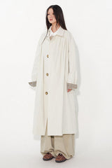 Waist-cinched, straight-cut, with a plaid patchwork design and raglan sleeves, this trench coat features a bold silhouette.
